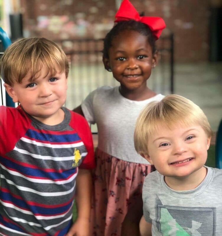 Three smiling children outside